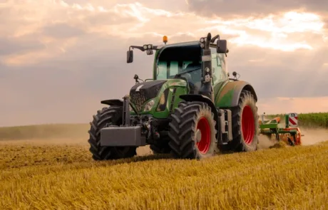 green tractor plowing cereal field 600nw 1923229541